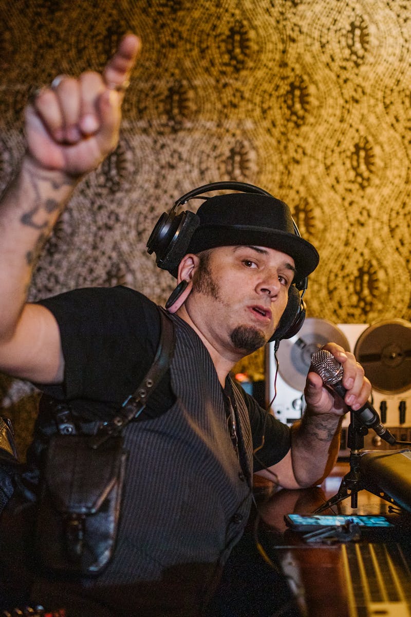 Music producer working with mixing console and microphone in a recording studio.